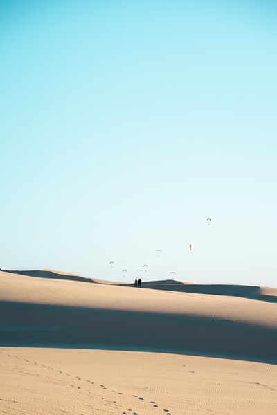 白天，人们在蓝天下的沙漠上行走
